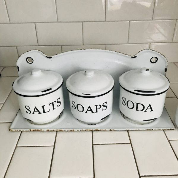 Vintage enameled bathroom storage containers in wall hanging rack with water closet with handle storage salts soda soap with lids