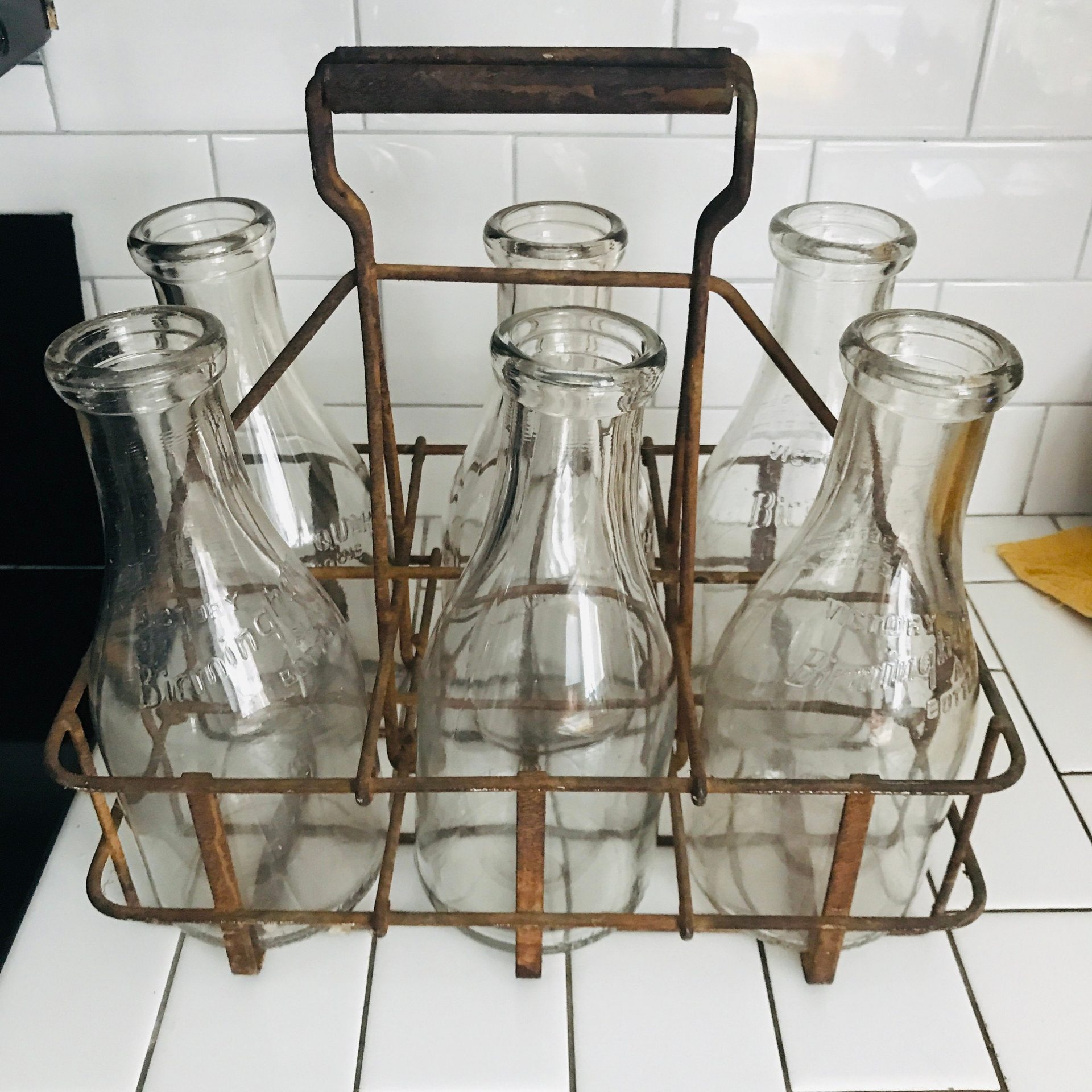 https://www.truevintageantiques.com/wp-content/uploads/2021/05/vintage-milk-bottles-in-metal-delivery-rack-6-quart-size-bottles-birmingham-farmhouse-rustic-collectible-kitchen-decor-60992a515-scaled.jpg